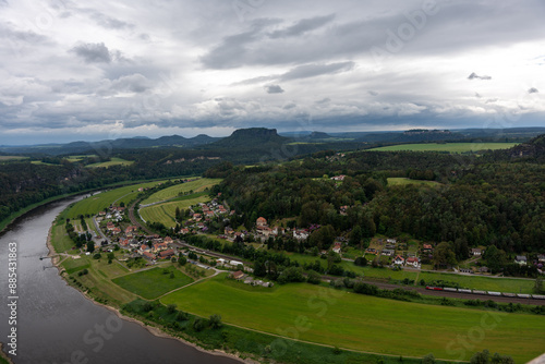 A town is situated on the banks of a river. The sky is cloudy and the town is surrounded by green fields photo