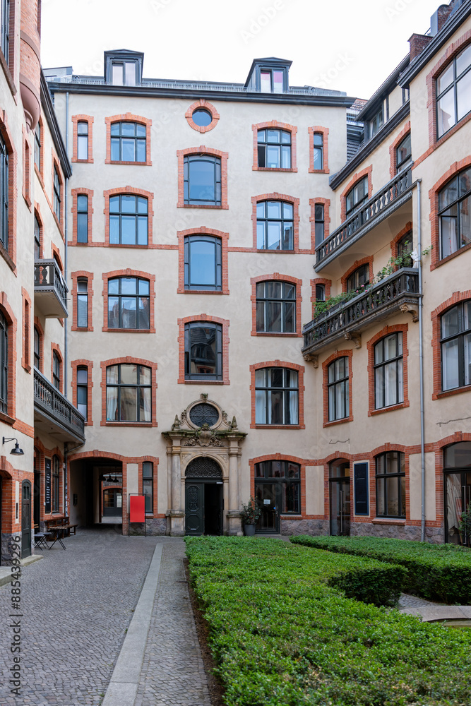 Obraz premium A courtyard with a building in the background. The building has a clock on the front. The courtyard is surrounded by a brick walkway
