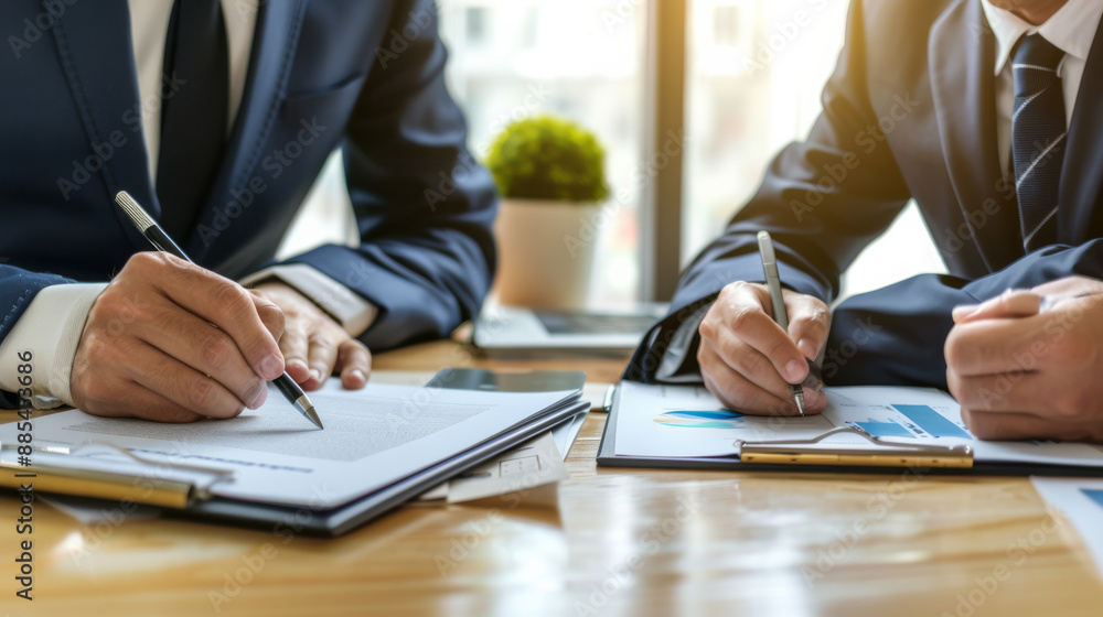 Three business professionals work together, reviewing documents at a wooden desk, representing teamwork and discussion. Three business professionals work together, reviewing documents at a wooden desk, representing teamwork and discussion.