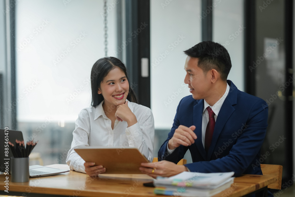 Two business professionals having a discussion in a modern office, reviewing documents and collaborating on a project. Two business professionals having a discussion in a modern office, reviewing documents and collaborating on a project.