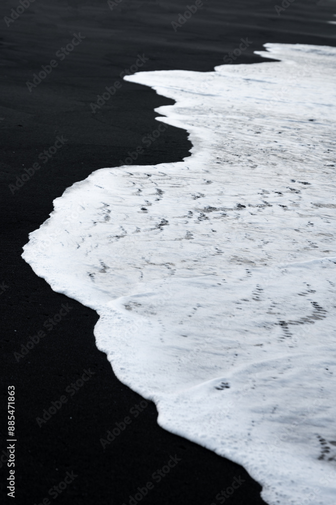 Close-up view of some waves crashing on a black sand beach. Natural background, wallpaper. Iceland.