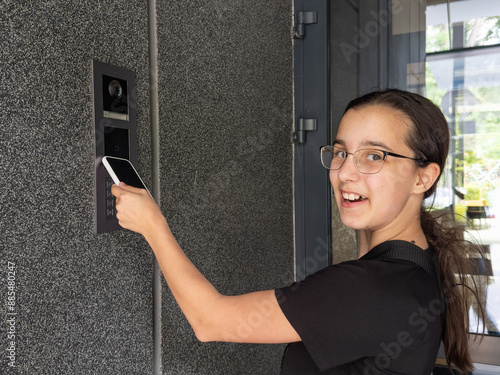 teenage girl using phone scan to digital door lock security systems at home.