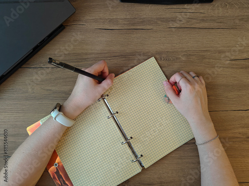 top view of woman writing in notebok on wooden table