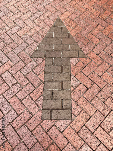 Brown brick arrow in red red bricks showing which diection to drive photo