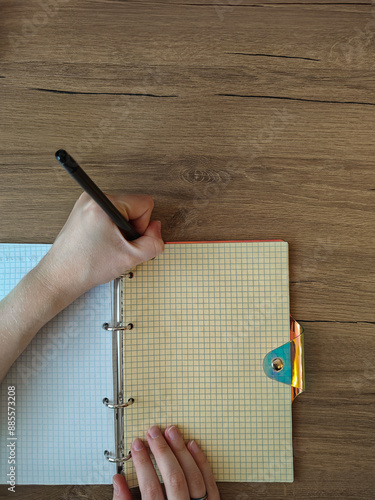 top view of woman writing in notebok on wooden table