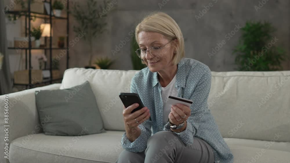 Mature senior woman buy online on mobile and use credit card on sofa Mature senior woman buy online on mobile and use credit card on sofa