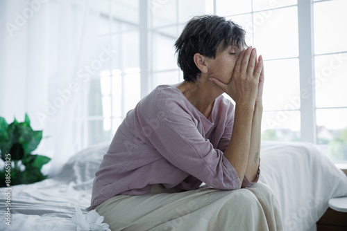 Foto Lonely mature woman sitting near napkins on bed at home