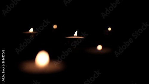 Round small candles in the dark. Lighting a candle, praying, hoping for the best. Religious atmosphere, candle fire on a black background photo