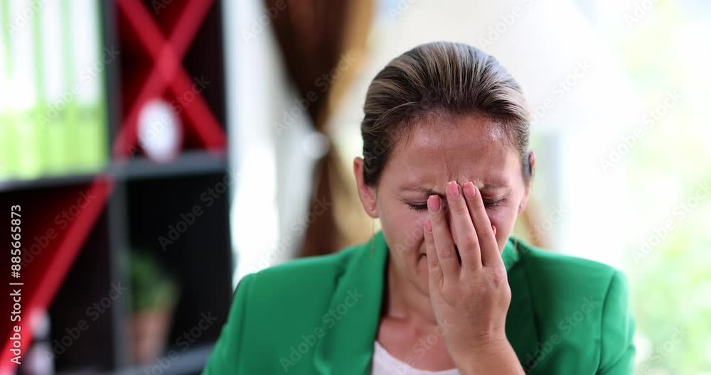 Sleepy woman yawns covering mouth with hand and closing eyes at workplace. Overworking female manager in green jacket sits at table feeling tired slow motion Sleepy woman yawns covering mouth with hand and closing eyes at workplace. Overworking female manager in green jacket sits at table feeling tired slow motion
