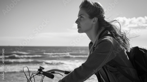 A person riding a bicycle on the sandy beach, with palm trees and ocean waves in the background