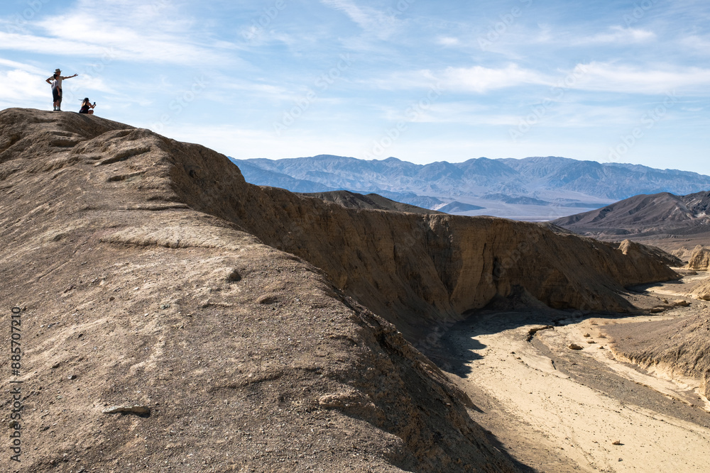 A woman and a man are standing on a hill overlooking a valley A woman and a man are standing on a hill overlooking a valley