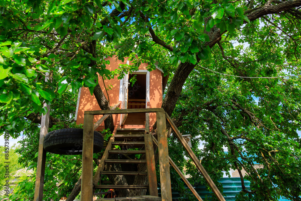 A tree house with a wooden staircase and a tire ladder A tree house with a wooden staircase and a tire ladder