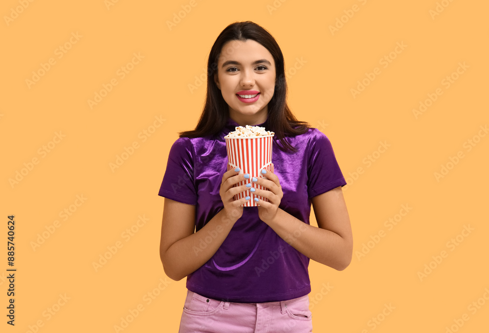 Beautiful young happy woman with bucket of popcorn on yellow background Beautiful young happy woman with bucket of popcorn on yellow background