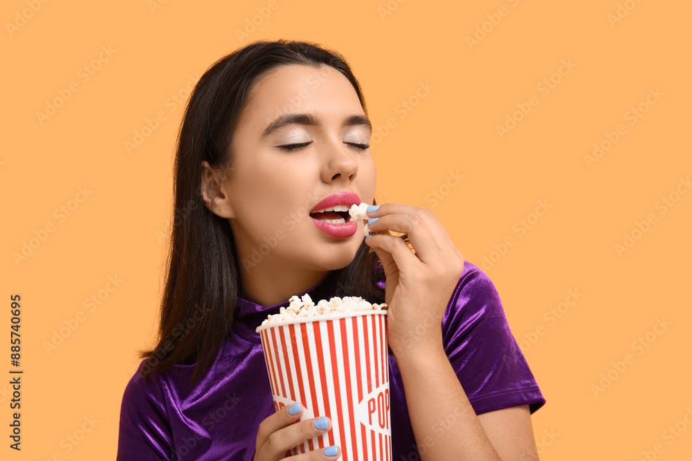 Beautiful young happy woman with bucket of popcorn on yellow background Beautiful young happy woman with bucket of popcorn on yellow background