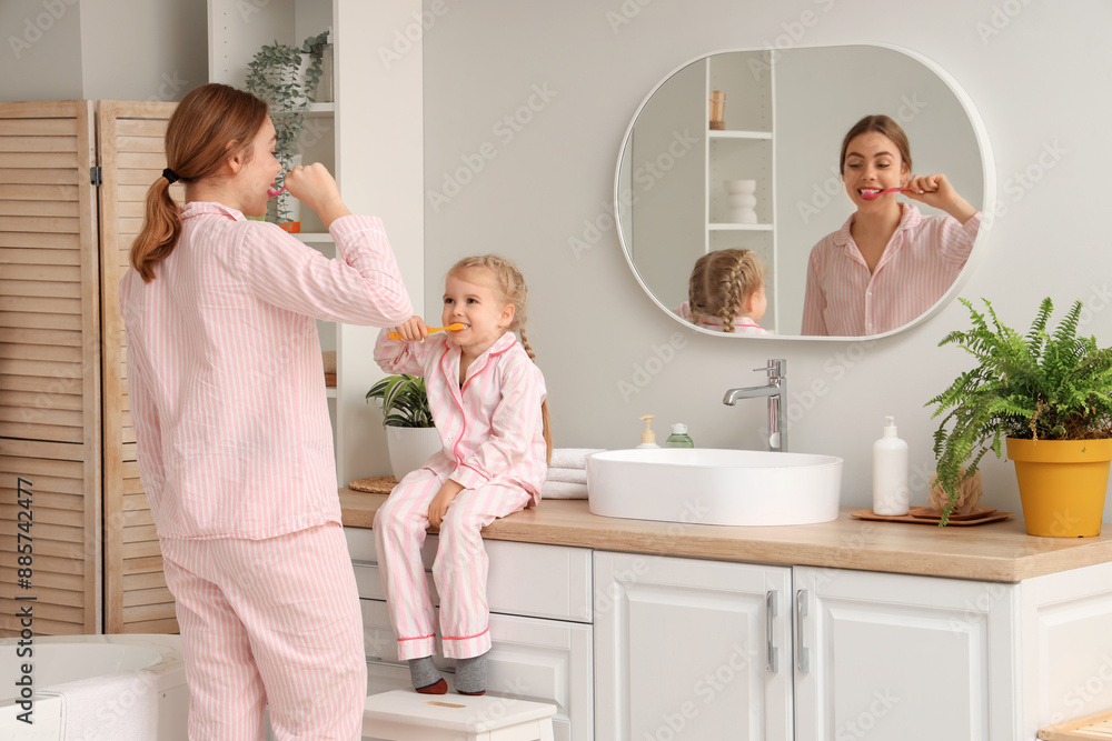 Fototapeta premium Young mother and her little daughter brushing teeth near mirror in bathroom