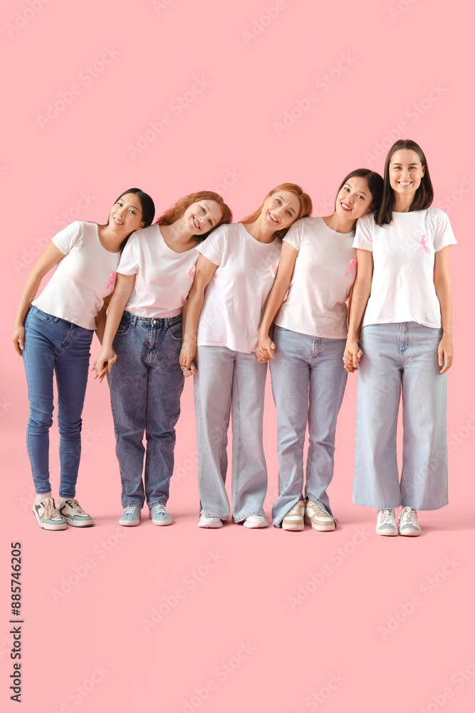 Obraz premium Beautiful women with pink ribbons holding hands on color background. Breast cancer awareness concept
