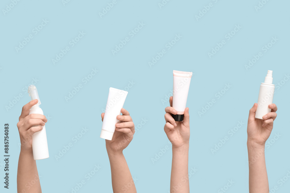 Female hands with different cosmetic products on blue background