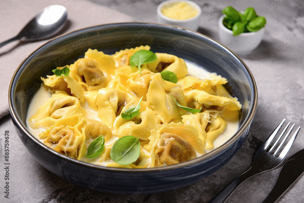 Bowl of boiled dumplings with sauce and basil on grey background Bowl of boiled dumplings with sauce and basil on grey background