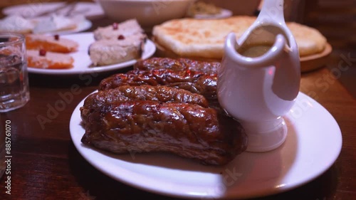 Sausages and kupat kupati, homemade sausage Traditional Georgian dish on Georgian traditional table in restaurant with tkemali sauce on plate. Georgian food in restaurant. photo