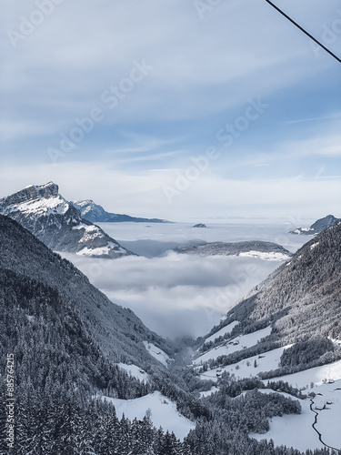 Snowy remote mountain valley above sea of fog