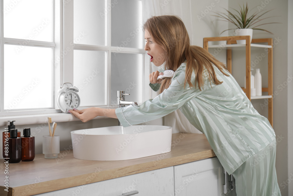 Shocked young woman in pajamas with hairbrush and alarm clock at home Shocked young woman in pajamas with hairbrush and alarm clock at home