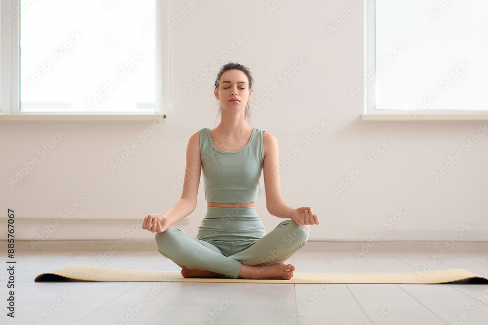 Beautiful young sporty woman meditating at home Beautiful young sporty woman meditating at home