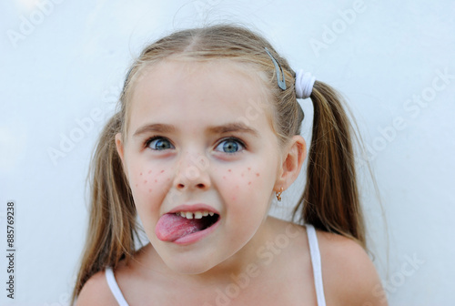 a mischievous, cheerful little girl with freckles rejoices and makes faces