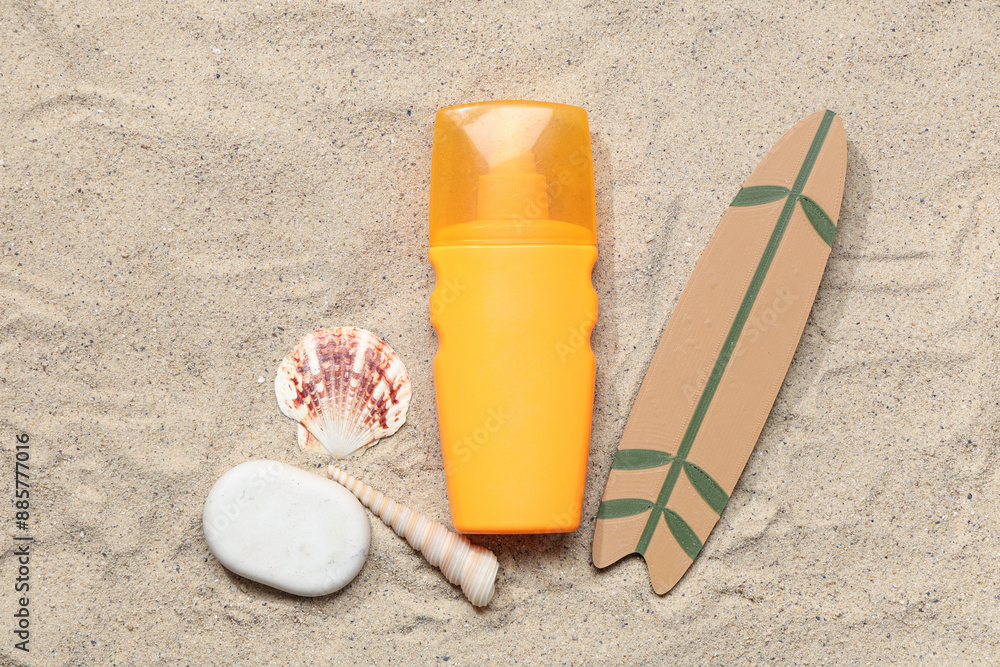 Bottle of sunscreen cream, seashells and mini surfboard on sand Bottle of sunscreen cream, seashells and mini surfboard on sand