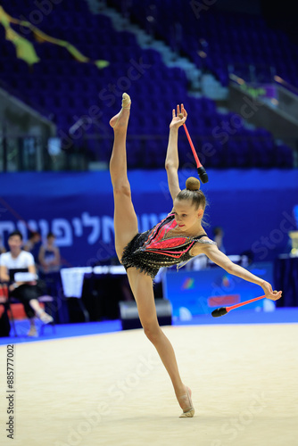 A graceful rhythmic gymnast showcases her skills with a club at an international competition