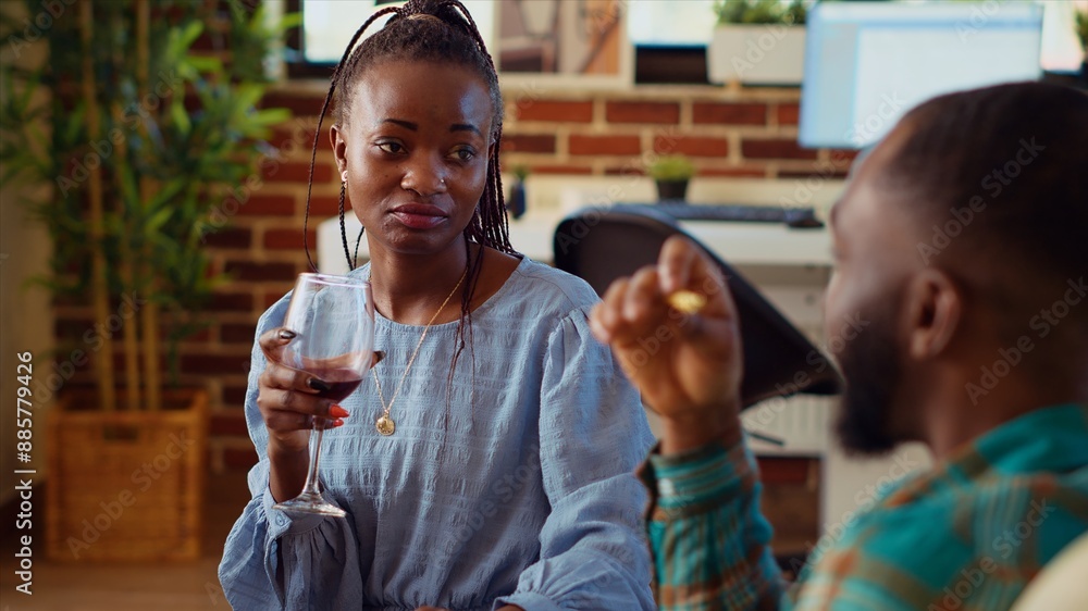 African american man waiting for guests to arrive at social gathering, talking with his girlfriend on couch. Husband and wife throwing apartment party for their friends in brick wall home African american man waiting for guests to arrive at social gathering, talking with his girlfriend on couch. Husband and wife throwing apartment party for their friends in brick wall home