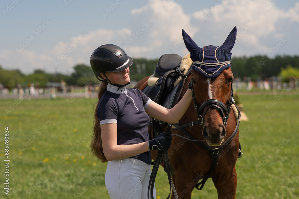 Fototapeta premium A young girl stands next to a horse before an equestrian competition. 