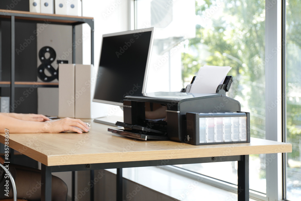 Fototapeta premium Businesswoman with computer and printer working at table in office, closeup