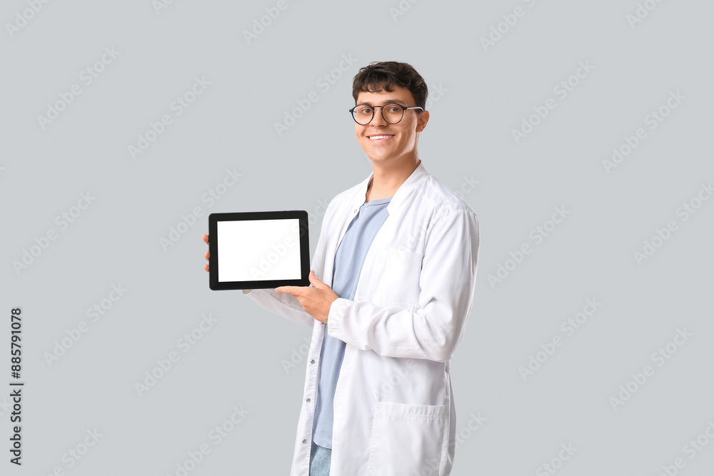 Male medical student with modern tablet computer on grey background Male medical student with modern tablet computer on grey background