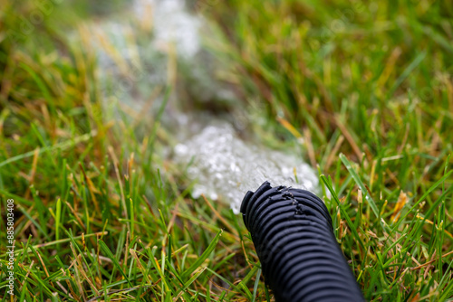 Foto Residential sump pump drain line discharging water into grass yard after a rains