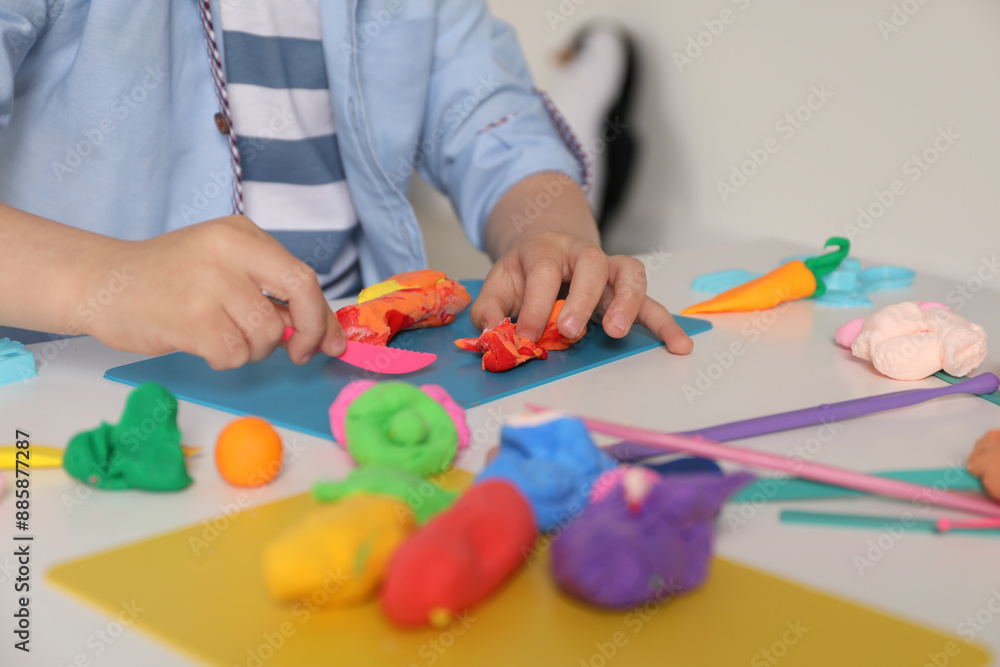 Little boy sculpting with play dough at table indoors, closeup Little boy sculpting with play dough at table indoors, closeup