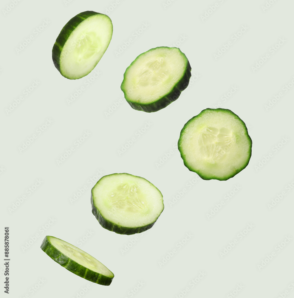 Fresh cucumber slices in air on light grey background Fresh cucumber slices in air on light grey background