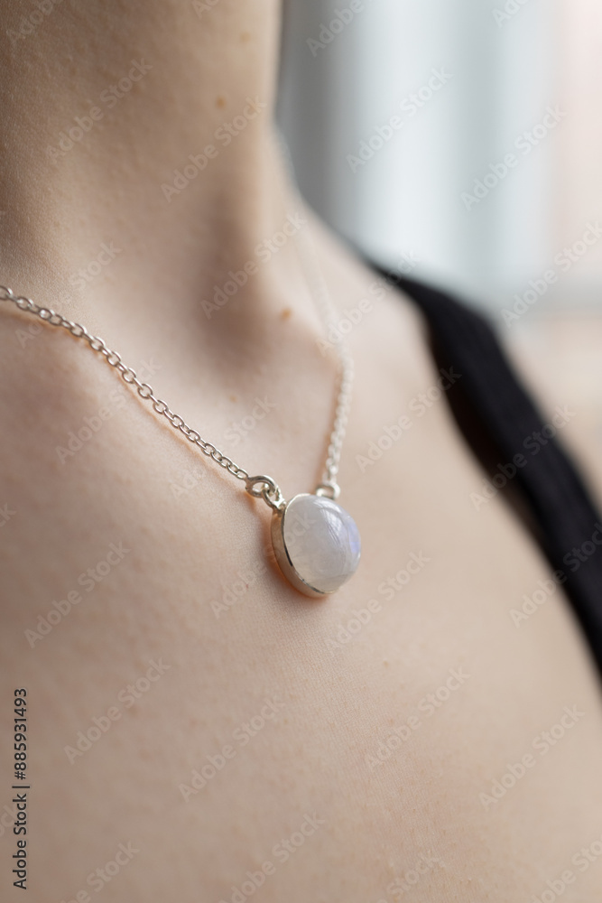 Silver necklace with moonstone on female neck. Model posing with jewelry. Elegant shiny pendant on young woman chest Silver necklace with moonstone on female neck. Model posing with jewelry. Elegant shiny pendant on young woman chest