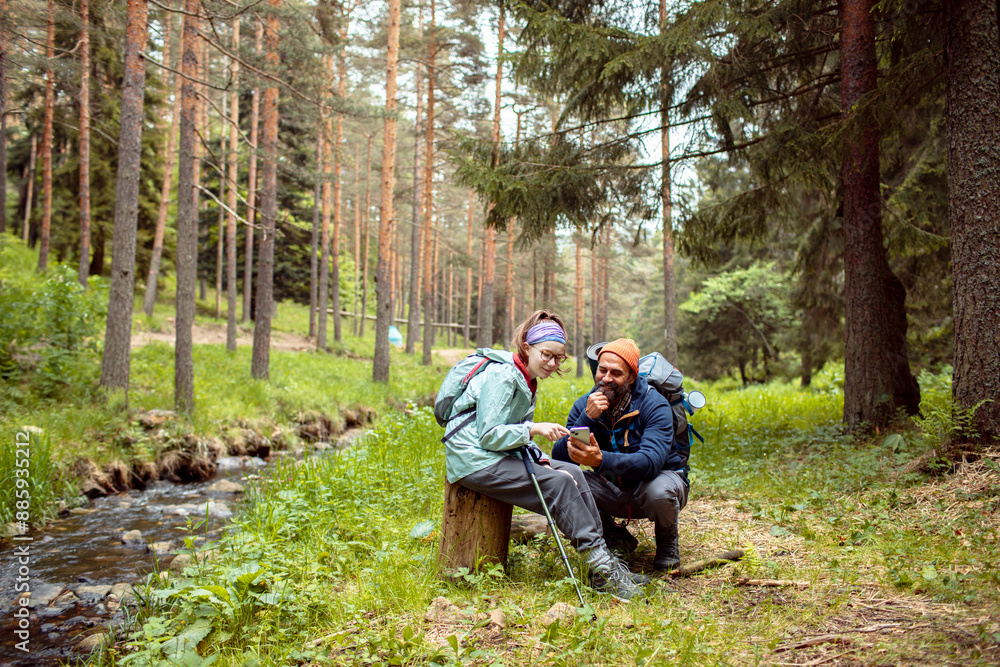 Father and daughter hiking in the forest using smartphone GPS Father and daughter hiking in the forest using smartphone GPS