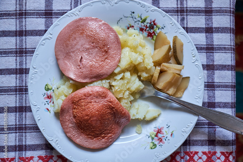 Traditional meal with mashed potatoes, fried bologna sausage (parizer), and pickles on a floral plate photo