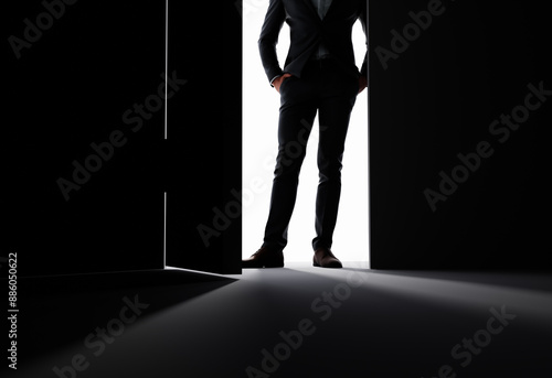 Tableau sur toile A man stands in the doorway of a large ajar door in the rays of light