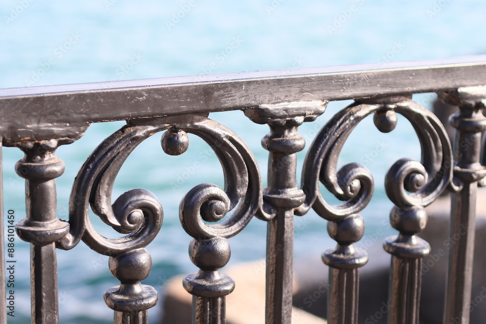 Close-up of a metal railing with a calm body of water in the background, suitable for use in various contexts. Close-up of a metal railing with a calm body of water in the background, suitable for use in various contexts.
