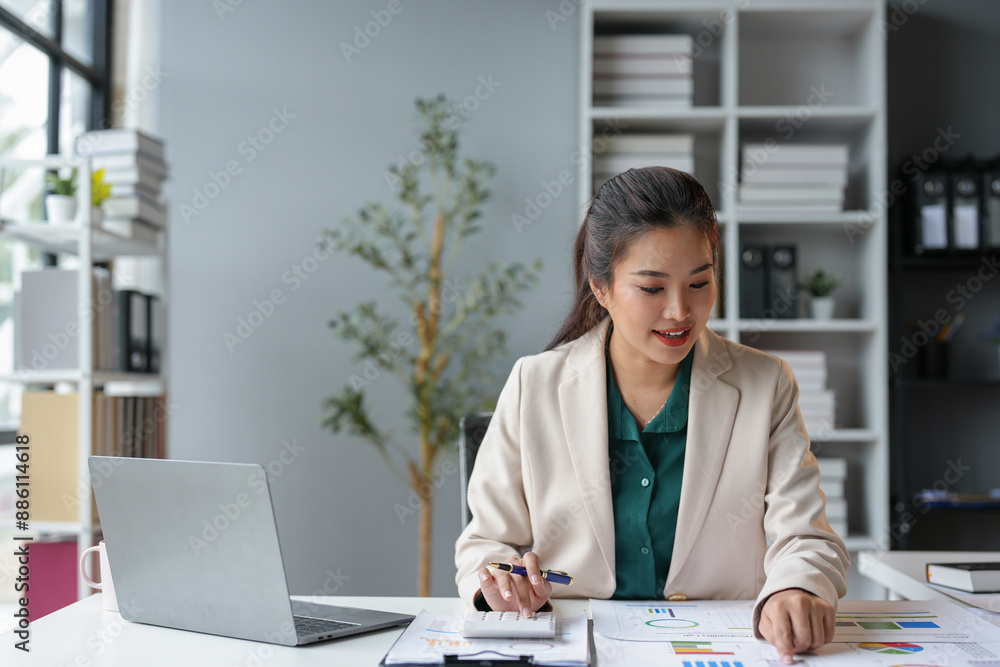 Asian business woman happily recording data on laptop Details from the graph Business income charts in real estate, taxes, management, technology marketing online in the office. Asian business woman happily recording data on laptop Details from the graph Business income charts in real estate, taxes, management, technology marketing online in the office.