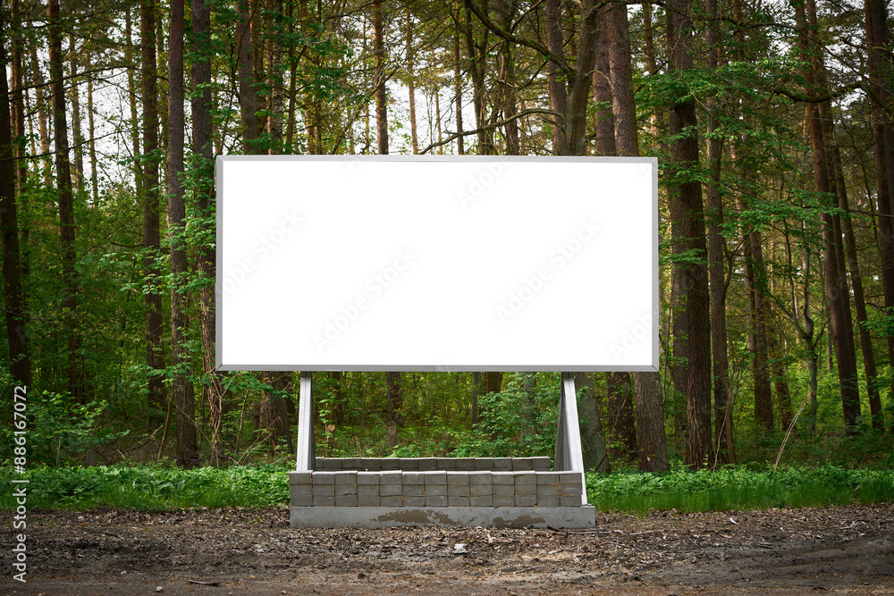 Fototapeta premium Blank billboard in lush forest offers perfect advertising space