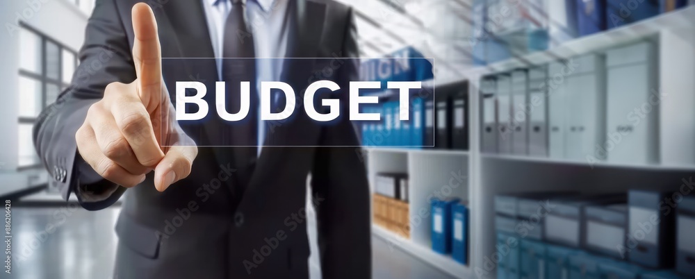 A businessman in suit pointing at virtual word budget showing budget concept A businessman in suit pointing at virtual word budget showing budget concept