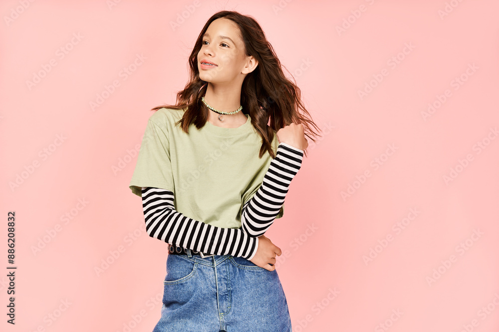 A stylish teenage girl in vibrant attire striking a pose in front of a vibrant pink background. A stylish teenage girl in vibrant attire striking a pose in front of a vibrant pink background.