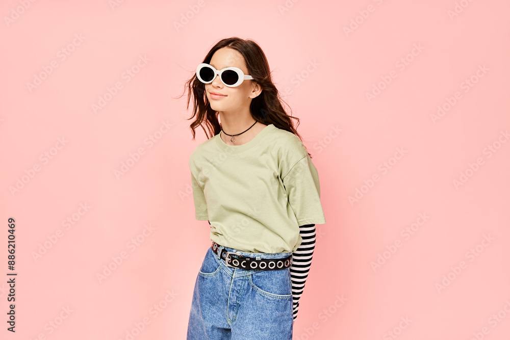 Fototapeta premium A stylish teenage girl confidently poses in a green shirt and sunglasses, exuding a vibrant and energetic aura.