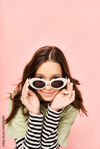 A fashionable teenage girl in vibrant attire poses confidently with sunglasses on her face.