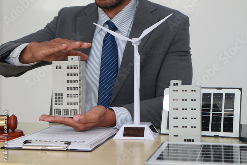 A businessman in a suit sits at a table discussing the Clean Energy Act, which incentivizes renewable energy adoption, clean raw material use in energy production, and energy-efficient transportation. photo