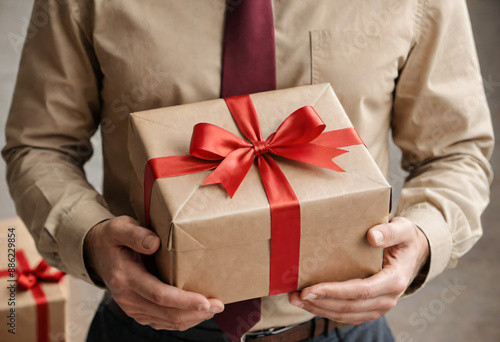 Man holding a kraft paper gift box tied red ribbon