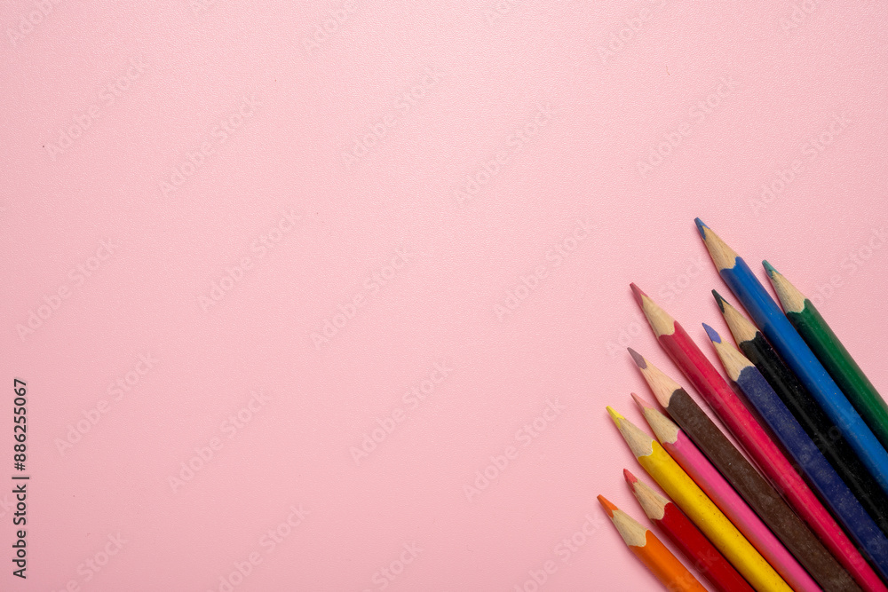 A row of colorful pencils on a pink background A row of colorful pencils on a pink background